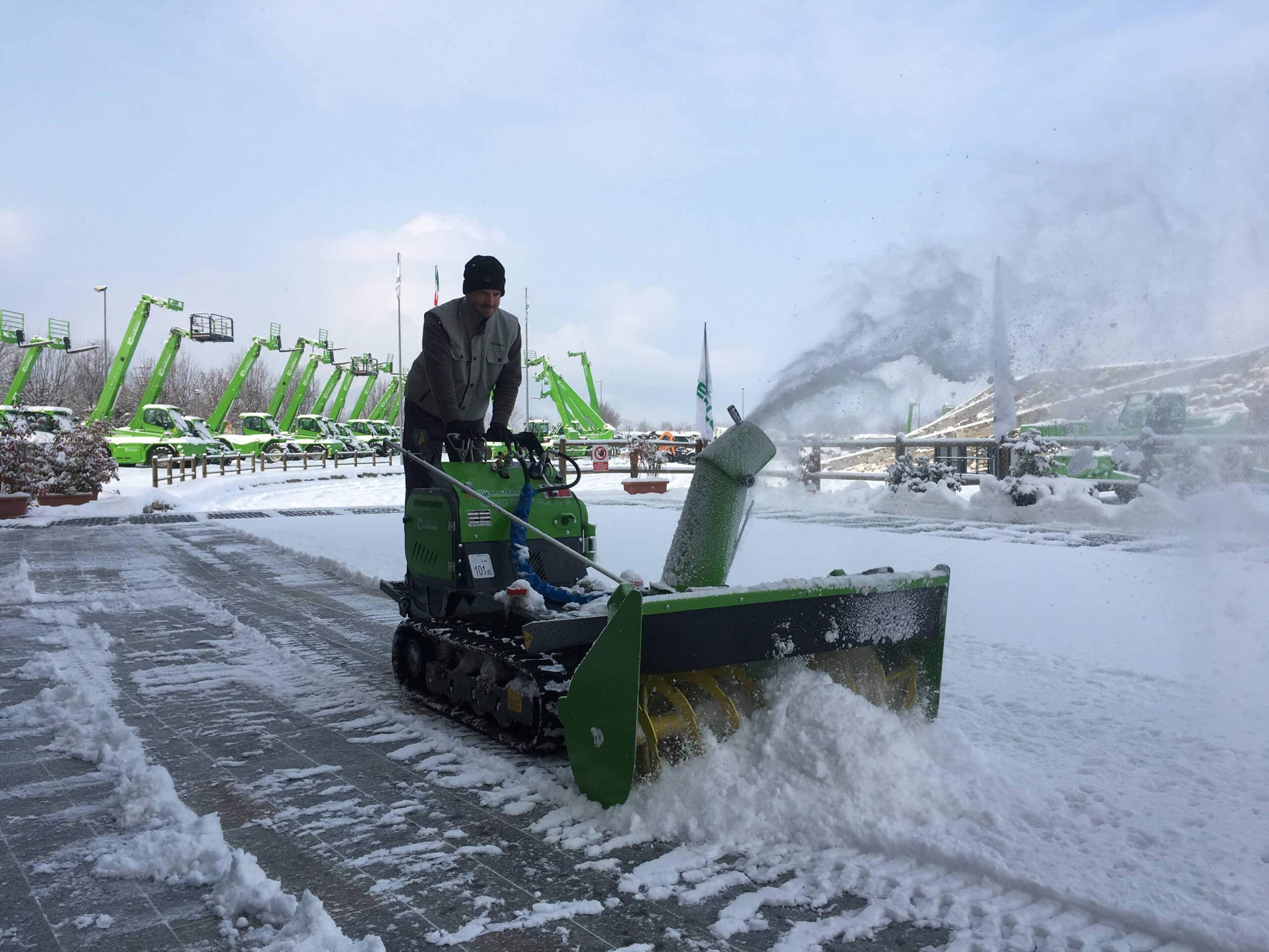 Merlo Cingo 8.3EVO rupsdumper met sneeuwruimer aanbouwdeel in actie tijdens het sneeuwvrij maken van een parkeerterrein.