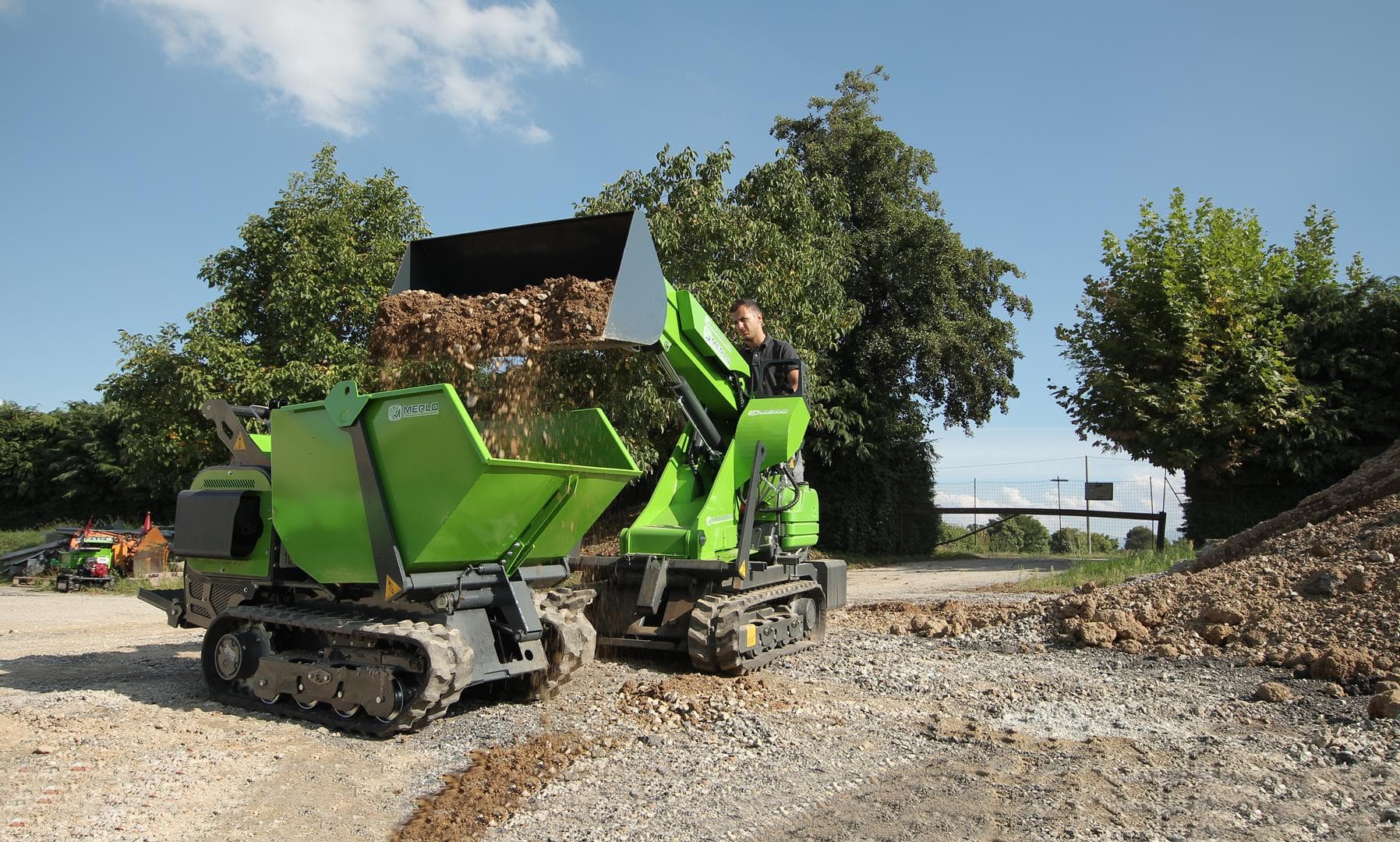 Merlo Cingo M500 rupsdumper die grondmateriaal overlaadt op een andere Merlo Cingo M500 rupsdumper.