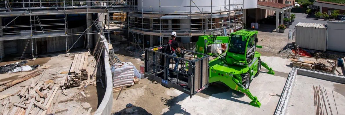 Merlo ROTO 40.16 roterende verreiker met werkkooi op bouwplaats.