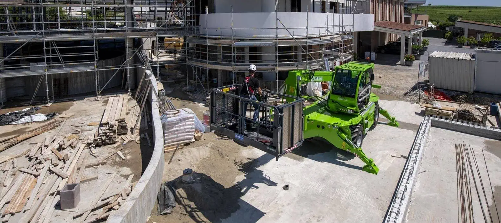 Merlo ROTO 40.18 roterende verreiker met werkkooi op bouwplaats.