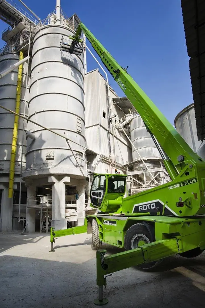 Merlo ROTO 70.28S roterende verreiker met uitgeschoven mast en werkkooi in industriële faciliteit