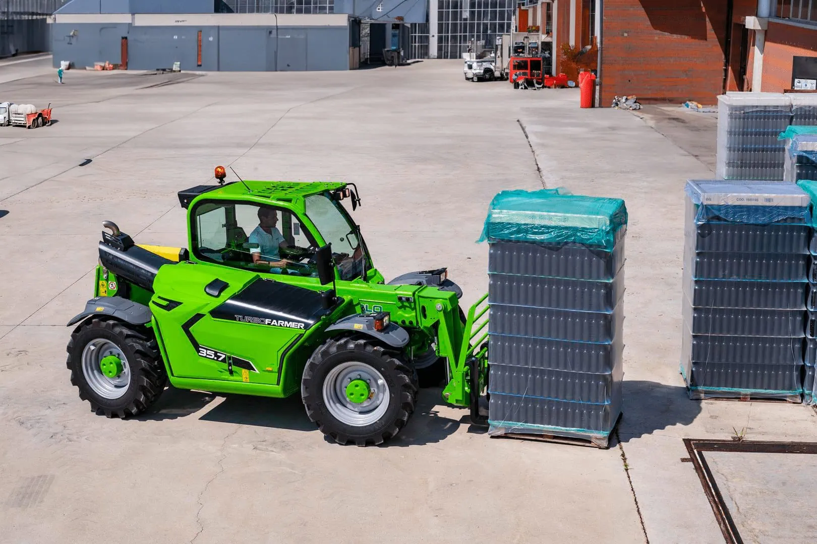 Merlo Turbofarmer 35.7 starre verreiker vervoert een pallet op industrieel terrein