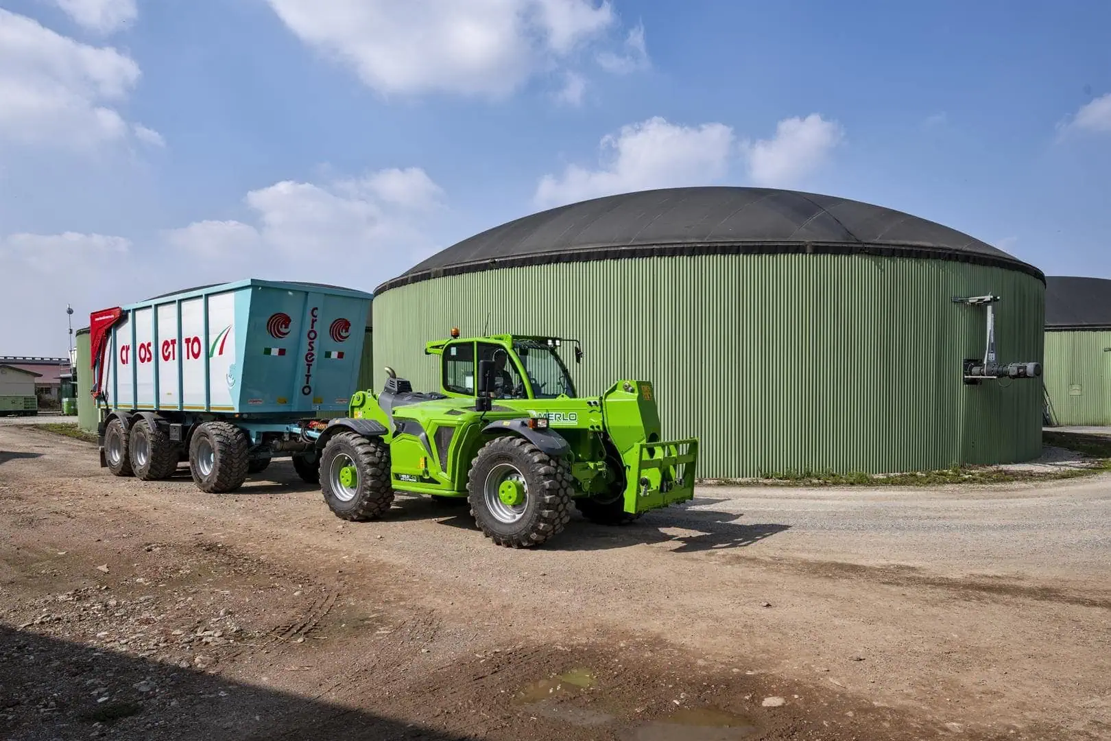 Merlo Turbofarmer 65.9 verreiker met aanhangwagen op boerderijterrein.