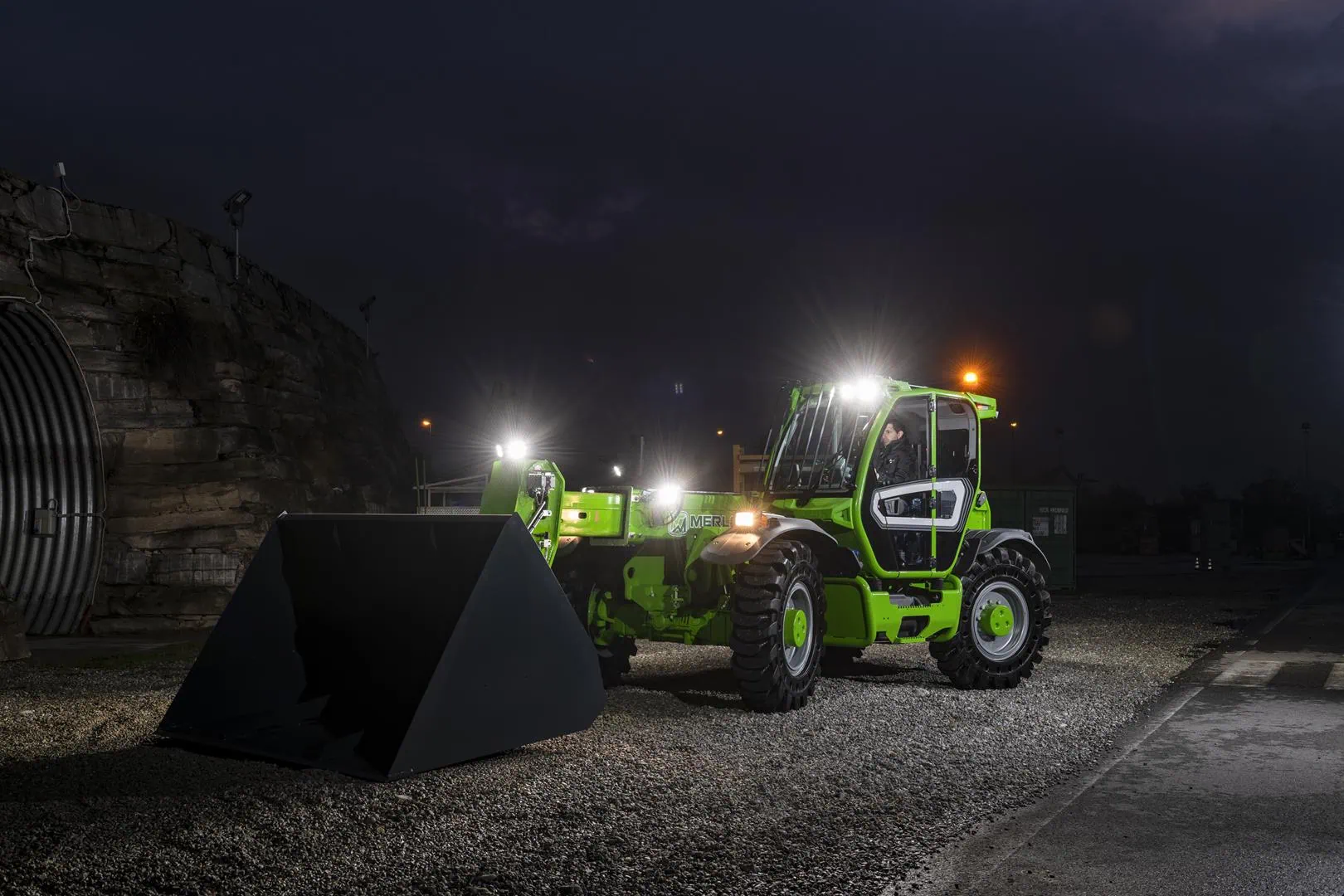 Merlo Turbofarmer 65.9 verreiker met schepbak tijdens nachtwerk.