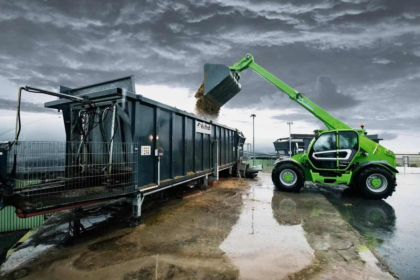 Merlo Turbofarmer 65.9 verreiker leegt schepbak in aanhangwagen.